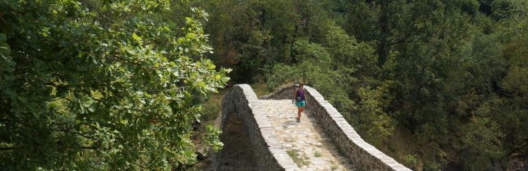 walker on stone bridge on the Fidenza-Pontremoli section of Via Francigena