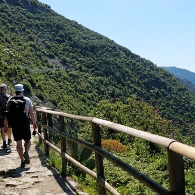 Hikers walking along a coastal path between Monterosso and Vernazza, with panoramic views over the Ligurian Sea