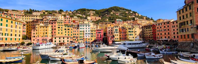 Colorful harbor of Camogli with fishing boats and pastel houses along the Ligurian coast, a gateway to hiking Cinque Terre