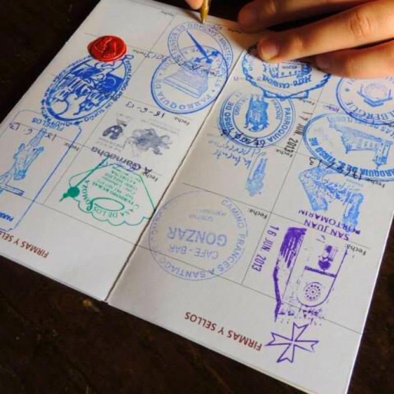 Pellegrino in cammino sotto un cielo blu sulla strada da Sarria a Santiago