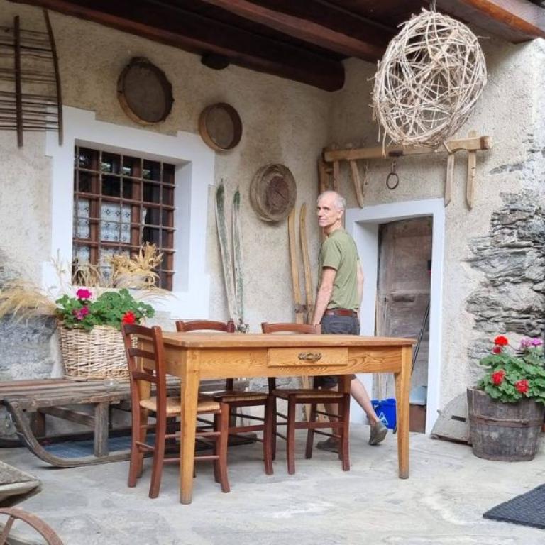 una persona in un cortile rustico in una delle borgate della Valle Maira, una valle alpina situata in Piemonte, in provincia di Cuneo