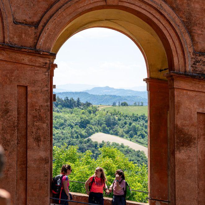 View over the Appennines framed by a historic arch along the Via degli Dei route