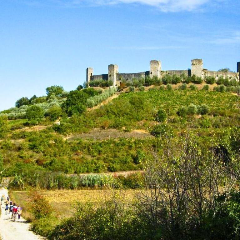 People walking on an walking path of Via Francigena toward Monteriggioni
