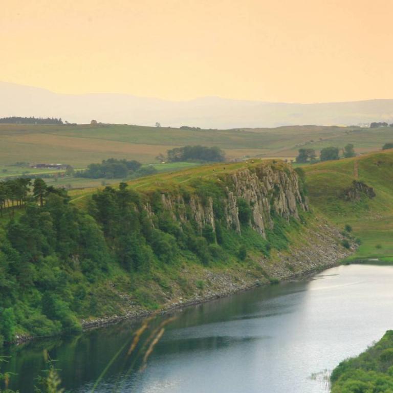 Veduta del paesaggio britannico con il muro al tramonto –Il Vallo di Adriano sullo sfondo di colline, cielo dorato