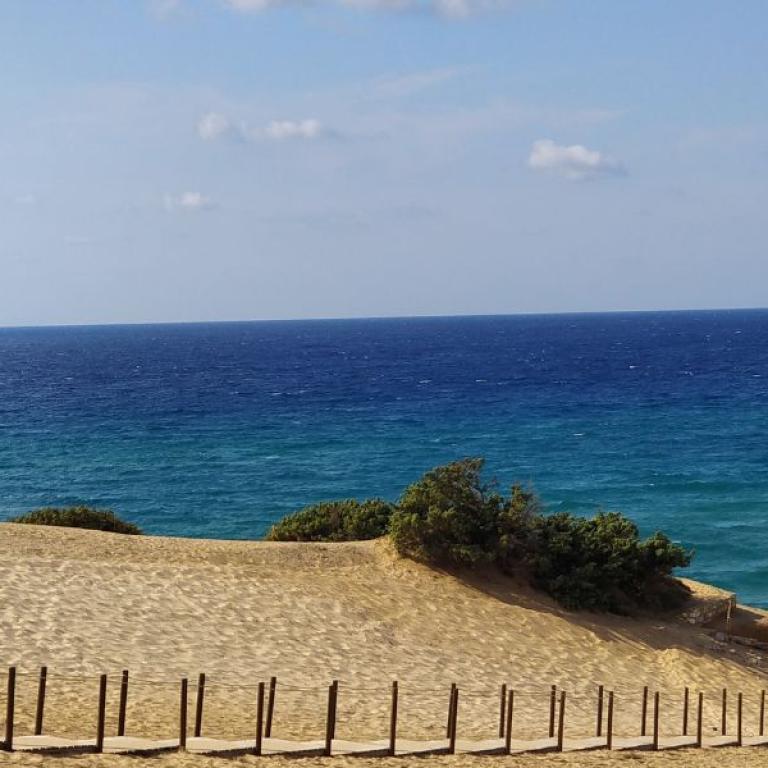 Walker crossing golden dunes above the bright turquoise sea on the island’s untouched western coast