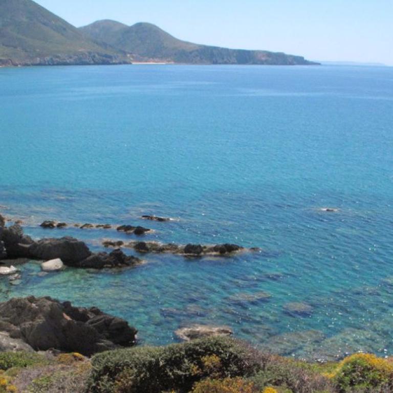 Walker crossing golden dunes above the bright turquoise sea on the island’s untouched western coast