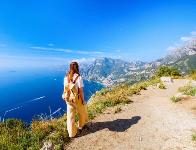 Woman walking on stunning path over Amalfi southern Italy