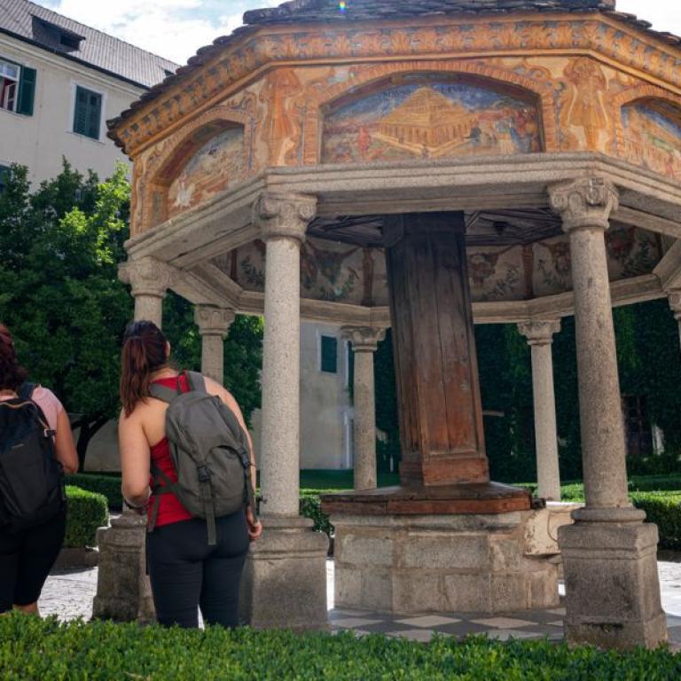 Travelers exploring a historic courtyard and ancient architecture in Bressanone along the Sentiero del Castagno route.