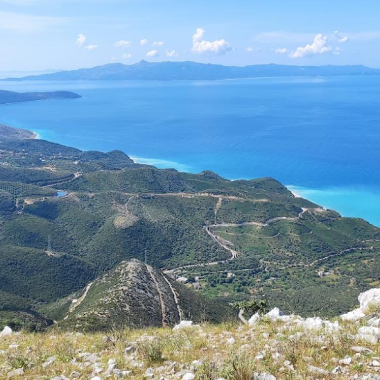 View over green hills and the turquoise Ionian Sea along the Albania Coastal trail.