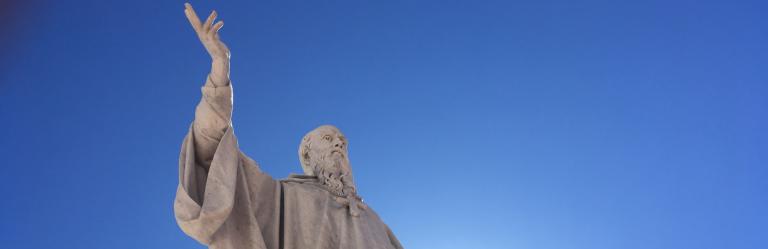Statua di San Benedetto contro un cielo blu intenso, simbolo del cammino di san benedetto.