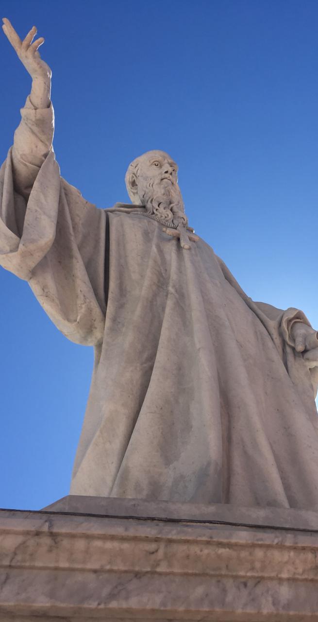 Statua di San Benedetto contro un cielo blu intenso, simbolo del cammino di san benedetto.