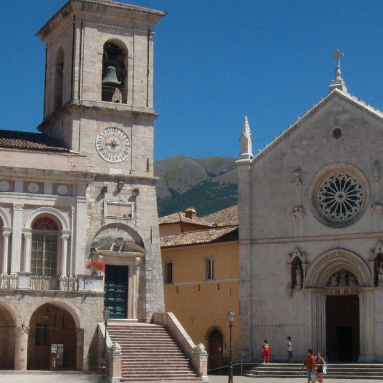 Facciata della basilica di Norcia illuminata dal sole, tappa storica del cammino di san benedetto.
